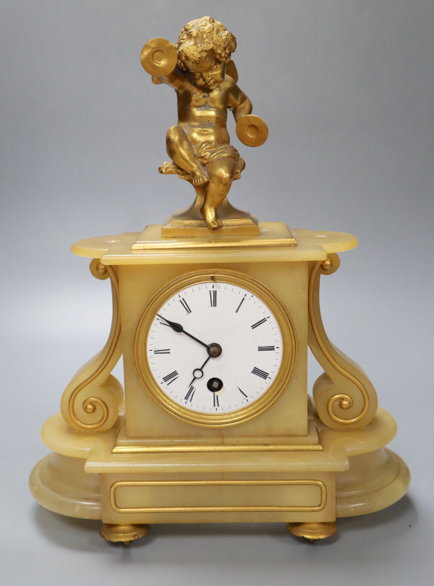 A late 19th century alabaster mantel clock, with gilt metal cherub surmount, French timepiece movement, 32cm